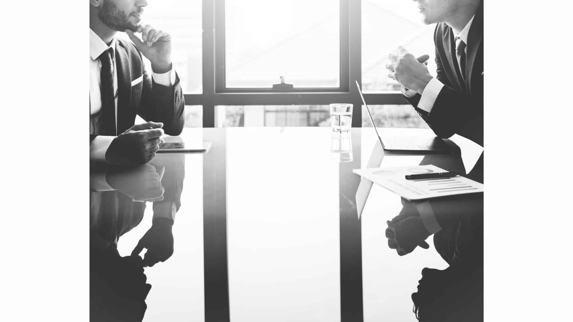 Deux consultants en discussion dans un bureau, avec ordinateur et documents