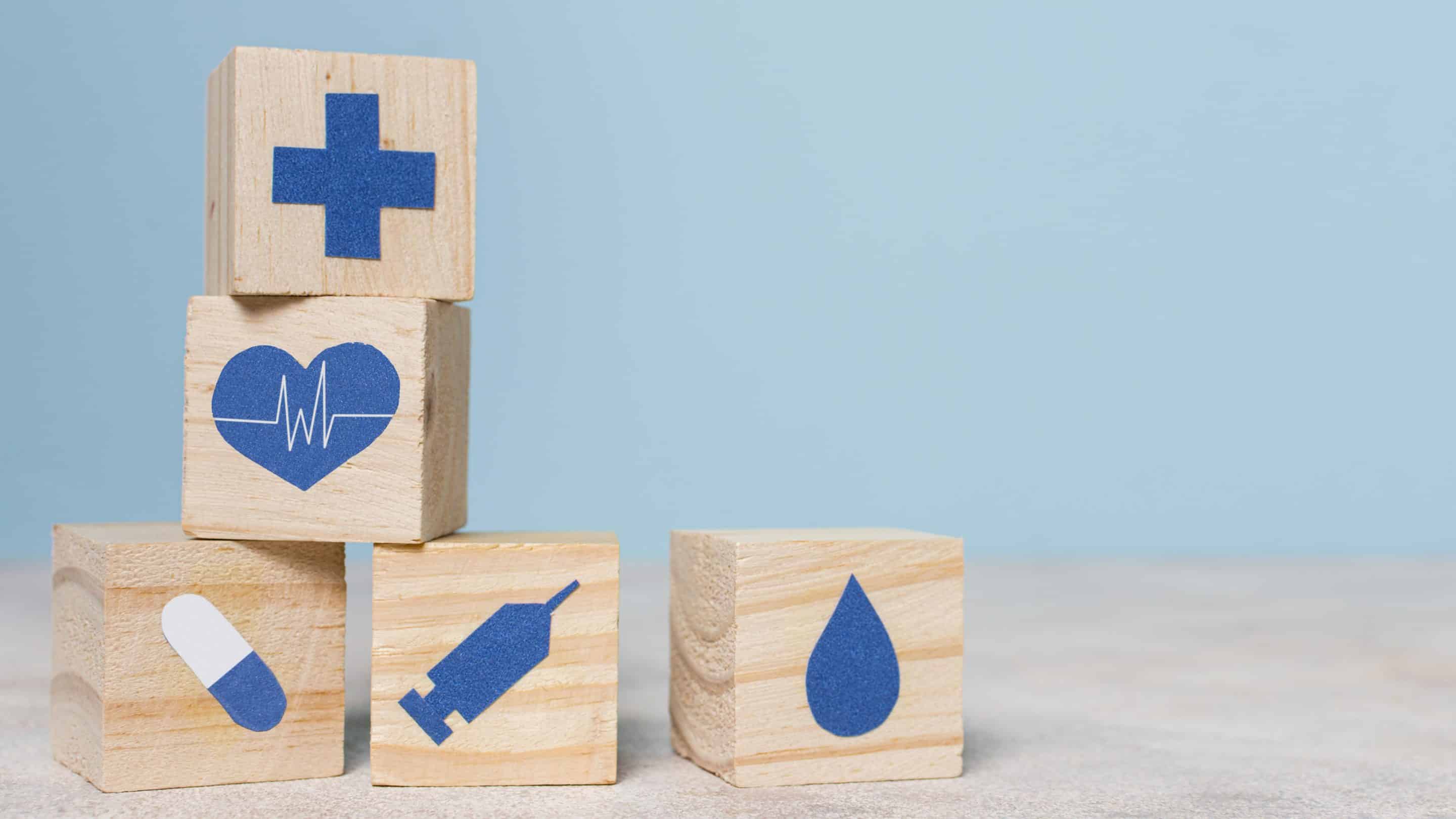 Illustration du secteur médico-social : cubes en bois représentant la santé (croix, cœur, médicament, seringue, goutte d’eau), symbolisant l’accompagnement des structures médico-sociales par MDP Data Protection pour la conformité RGPD et la protection des données sensibles.